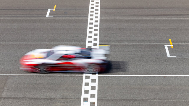 Motion blur race car racing on speed track, Car race on the international circuit race track crossing start and finish line, Race car crossing start and finish line, Target business achieve.