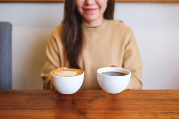 Closeup image of a young woman holding and serving two cups of hot coffee