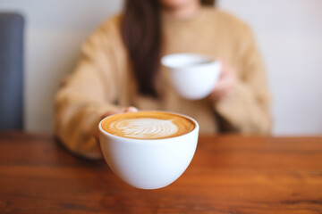 Closeup image of a woman holding and serving two cups of hot coffee