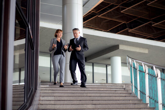 Two senior business man and woman in formal meeting and discussing documents and using a tablet in modern office, businessman planning with partner or consulting, business and team concept.