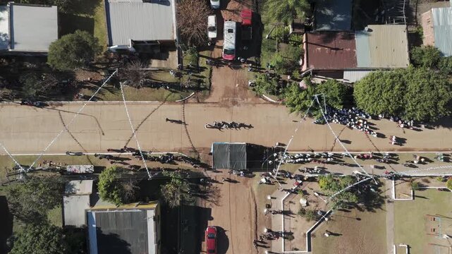 A zooming-in shot of a ceremony with a drone shot overlooking people in Argentina in a flag ceremony dancing chacarera