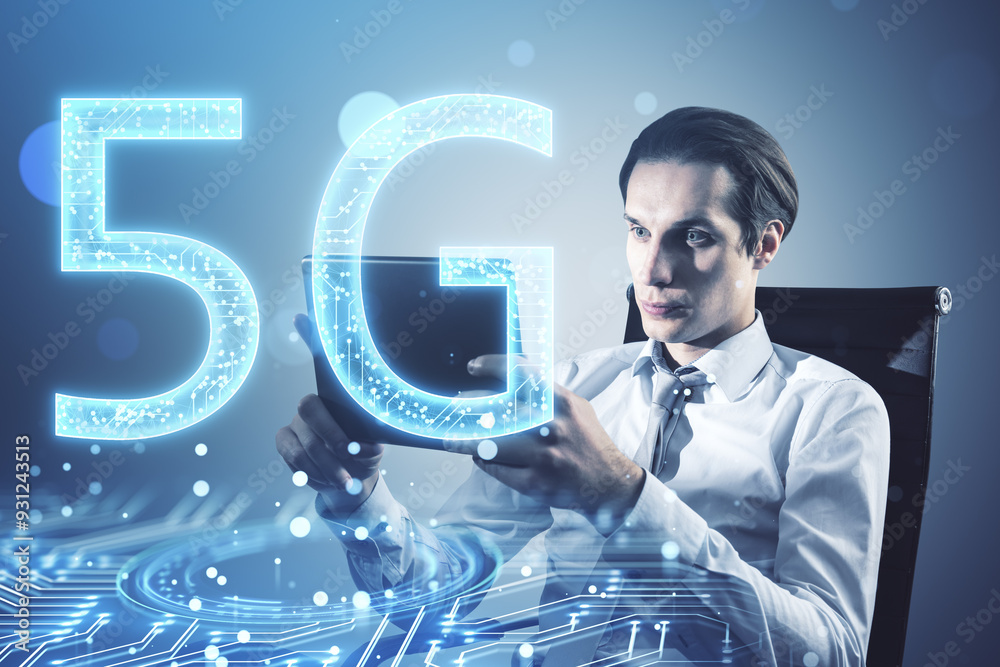 Poster attractive young european businessman sitting and using tablet with glowing 5g circuit hologram on b