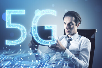Attractive young european businessman sitting and using tablet with glowing 5G circuit hologram on blurry bokeh circles background. Mobile internet speed concept. Double exposure.