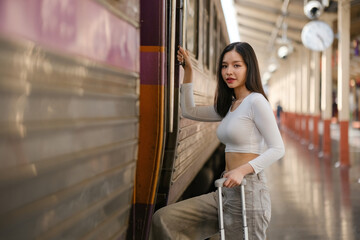 A woman is standing in front of a train with a suitcase