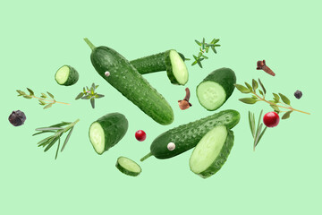 Ripe cucumbers, herbs and spices flying on light green background