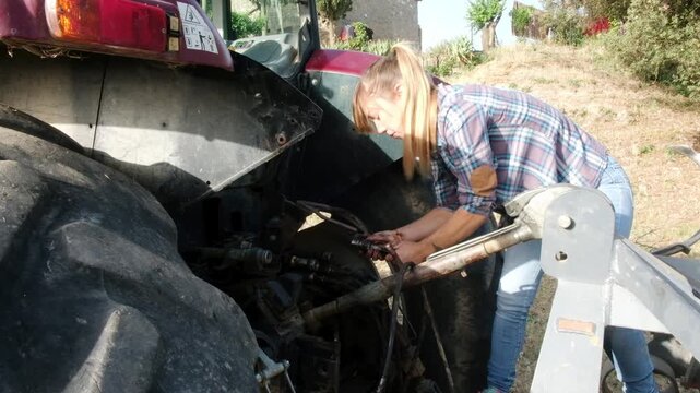 A young farmer mechanic works diligently to fix a tractor on her farm, showcasing her skills and dedication to agriculture.