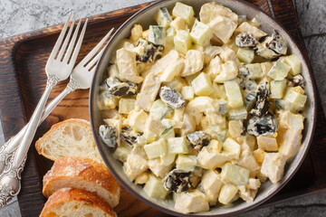 Delicious salad with chicken, prunes, cucumber and eggs close-up in a bowl on the table. Horizontal top view from above
