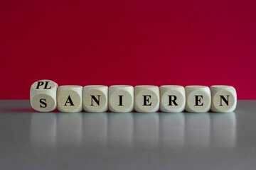 Turned dice and changes the German word 'sanieren' (renovate) to 'planieren' (flatten). Beautiful red background, gray table.