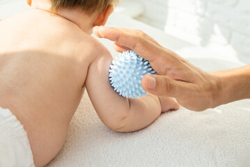 Dad making massage baby hands with a massage ball. Sensory, tactile development, activity muscles. Concept of taking care baby, fine motor skills. close up.