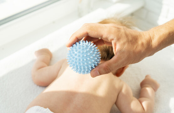 Dad making massage baby hands with a massage ball. Sensory, tactile development, activity muscles. Concept of taking care baby, fine motor skills. close up.