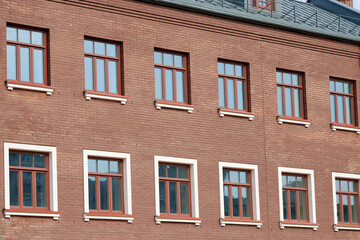 Red brick wall with symmetrical windows, architectural detail. Row of windows, symmetrical multiple windows, traditional architecture and urban design.