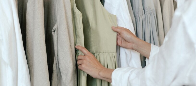 Close-up of female hands plucked hanger choosing clothes in clothing store. Middle aged woman runs across a rack of clothes in a shopping mall. Sale promotion and shopping concept. Part of the series.