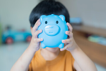 Photo of little cute preschool kid hold piggy bank over his face.  Wallet collect his first money savings