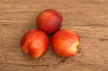 Trzy nektarynki leżą na stole, widok z góry 