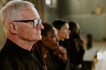Medium close up of silver-haired pastor profile during burial service