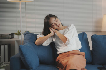 Young woman is taking a break from work, resting her head on her hands on the sofa