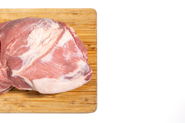 A piece of meat is on a wooden cutting board. The meat is cut into pieces and is ready to be cooked Pork meat isolated on a white background.