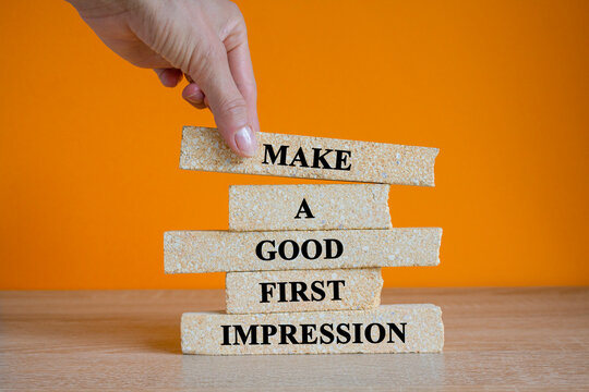 Concept words Make A Good First Impression on brick blocks. Beautiful wooden table orange background. Businessman hand. Business legacy and future concept.