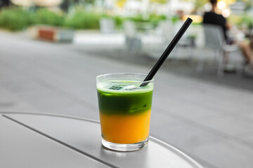 Two layered matcha with orange juice in a glass