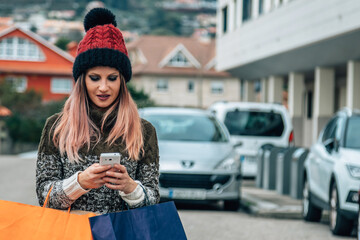 young woman with shopping bags and mobile phone on the street