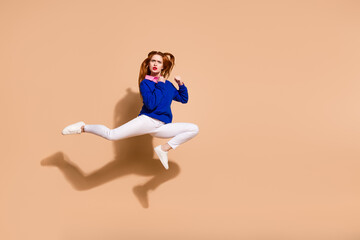 Full size photo of nice young woman jump fight empty space wear pullover isolated on beige color...