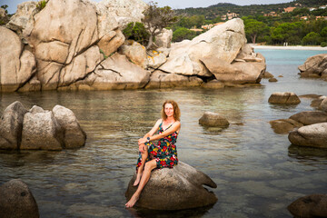 woman on beautiful beach with rocks watching sunset
