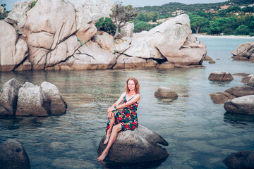 woman on beautiful beach with rocks watching sunset