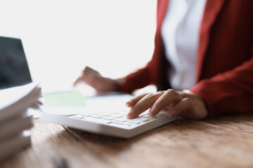 woman meticulously plans a finance audit, using a computer and calculator to review budget documents and ensure accuracy