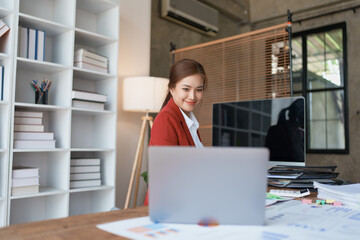 woman meticulously plans a finance audit, using a computer and calculator to review budget documents and ensure accuracy