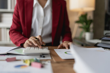 woman meticulously plans a finance audit, using a computer and calculator to review budget documents and ensure accuracy