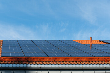 bunch of solar panels on roof during sunny day with blue sky