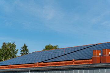 bunch of solar panels on roof during sunny day with blue sky