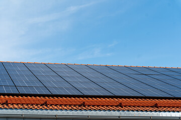 bunch of solar panels on roof during sunny day with blue sky
