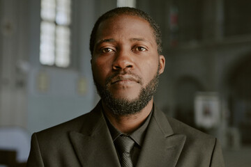 Naklejka premium Portrait of African American man dressed in black costume, he looking at camera with sorrow in eyes