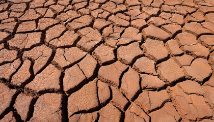 Cracked earth texture of ground, broken and rough surface red mud clay soil in summer season, crack ground floor on arid drought environment and hot weather in nature, light on top photo for graphic