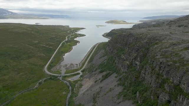 Drone footage of the road to Havoysund in Northern Norway in summer. A small bay and steep specific rocks.