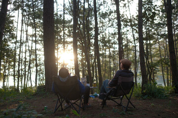 Two men sit and watch the sunrise in the forest. Royalty high-quality free best stock image of Enjoying adventure travel lifestyle, landscape outdoor in morning. Peaceful and quiet