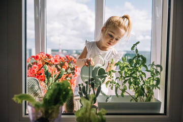 Little girl watering flowers on a sunny balcony in a bright, cheerful home setting