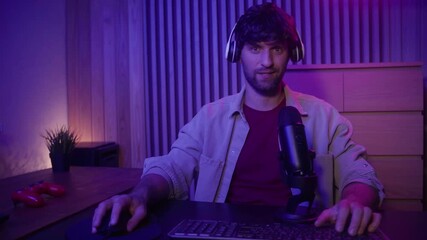 A gamer is actively participating in a live streaming session while speaking into a microphone. The setting features a stylish, dimly lit room with colorful lighting, creating an engaging atmosphere