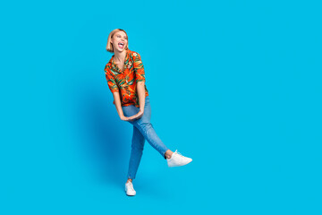 Photo of positive charming glad girl wear stylish print clothes have fun look empty space isolated on blue color background