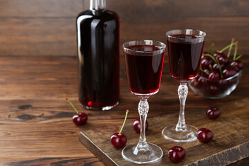 Delicious cherry liqueur and berries on wooden table