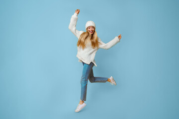 Emotional happy winter girl over yellow studio background, dancing and jumping