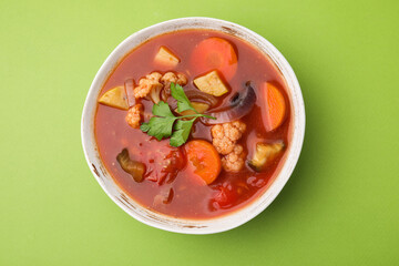 Delicious homemade stew in bowl on green background, top view