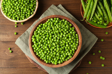 Fresh green peas and pods on wooden table, flat lay