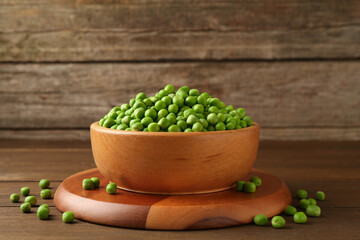 Fresh green peas in bowl on wooden table