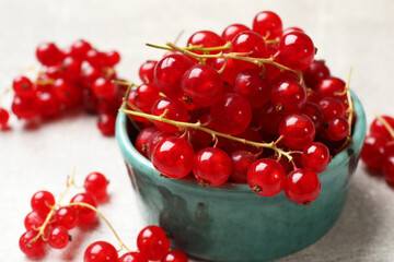 Fresh red currant in bowl on light table, closeup
