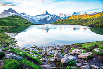 Fantastic landscape at sunrise with stones in the foreground on the lake in the Swiss Alps. Wetterhorn, Schreckhorn, Finsteraarhorn et Bachsee. Exciting places. (relaxation, harmony - concept).