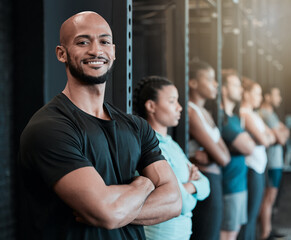 Fitness, gym and man in row for portrait, confidence and ready for workout in class. Arms crossed, personal trainer and smile in training center for exercise, wellness and determination for growth