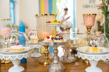 Dessert Delight: A Table of Temptation: A delightful spread of pastries and desserts under glass domes, a visual feast of sweet treats. A blur of a server in the background adds a touch of life to the