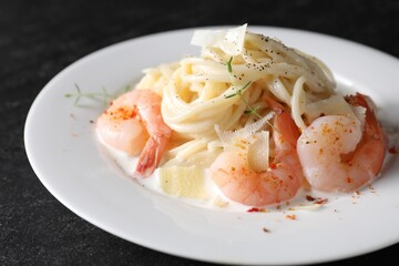 Delicious pasta with shrimps and cheese on black table, closeup